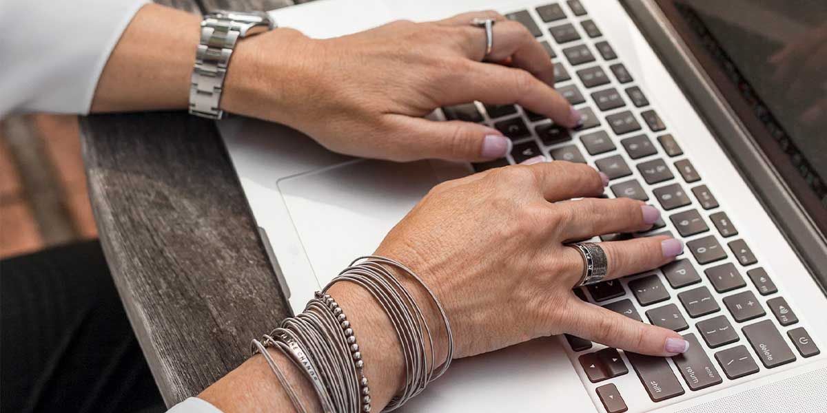 Hands on MacBook with a lot of sharp jewellery